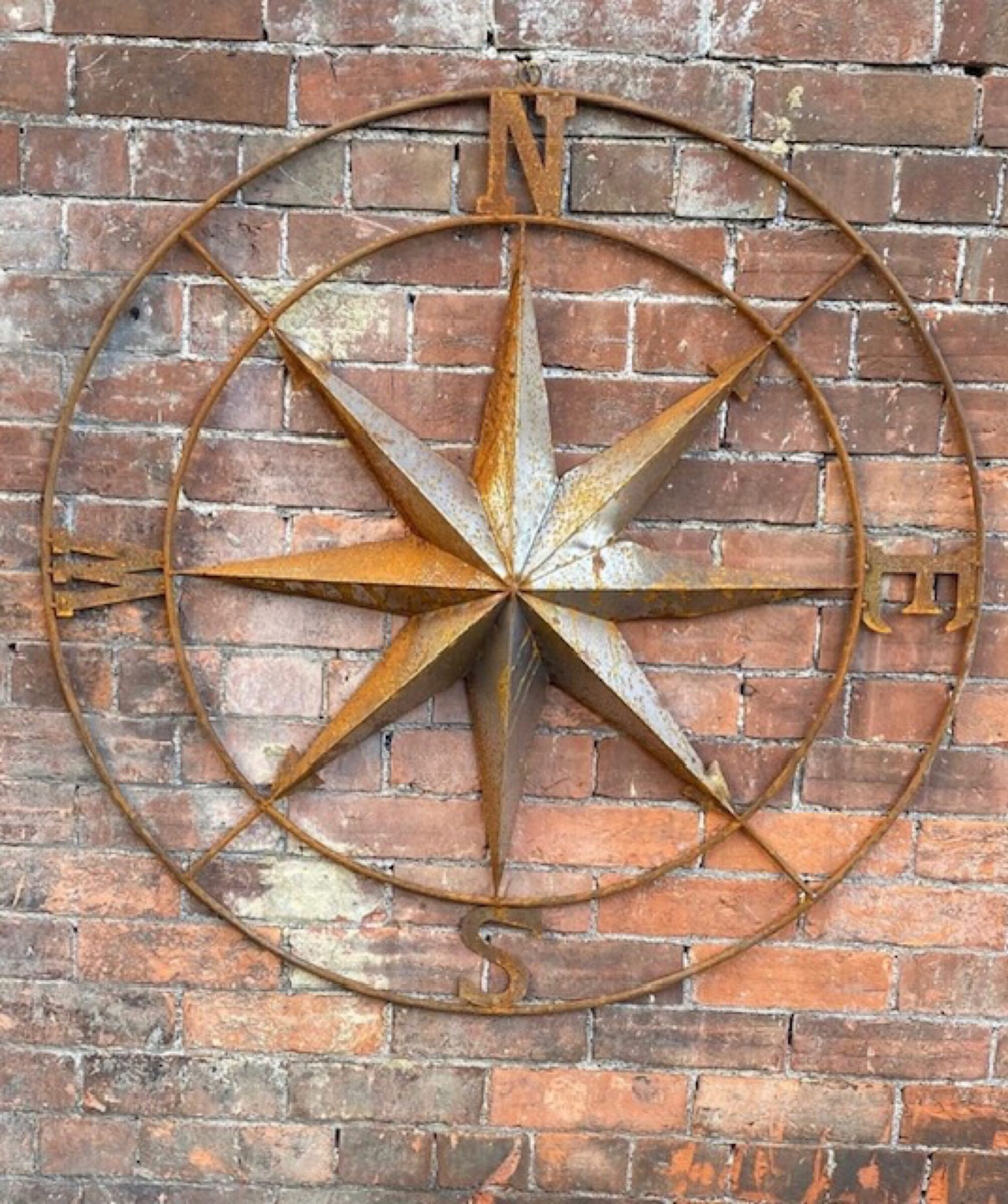 Metal compass on brick wall